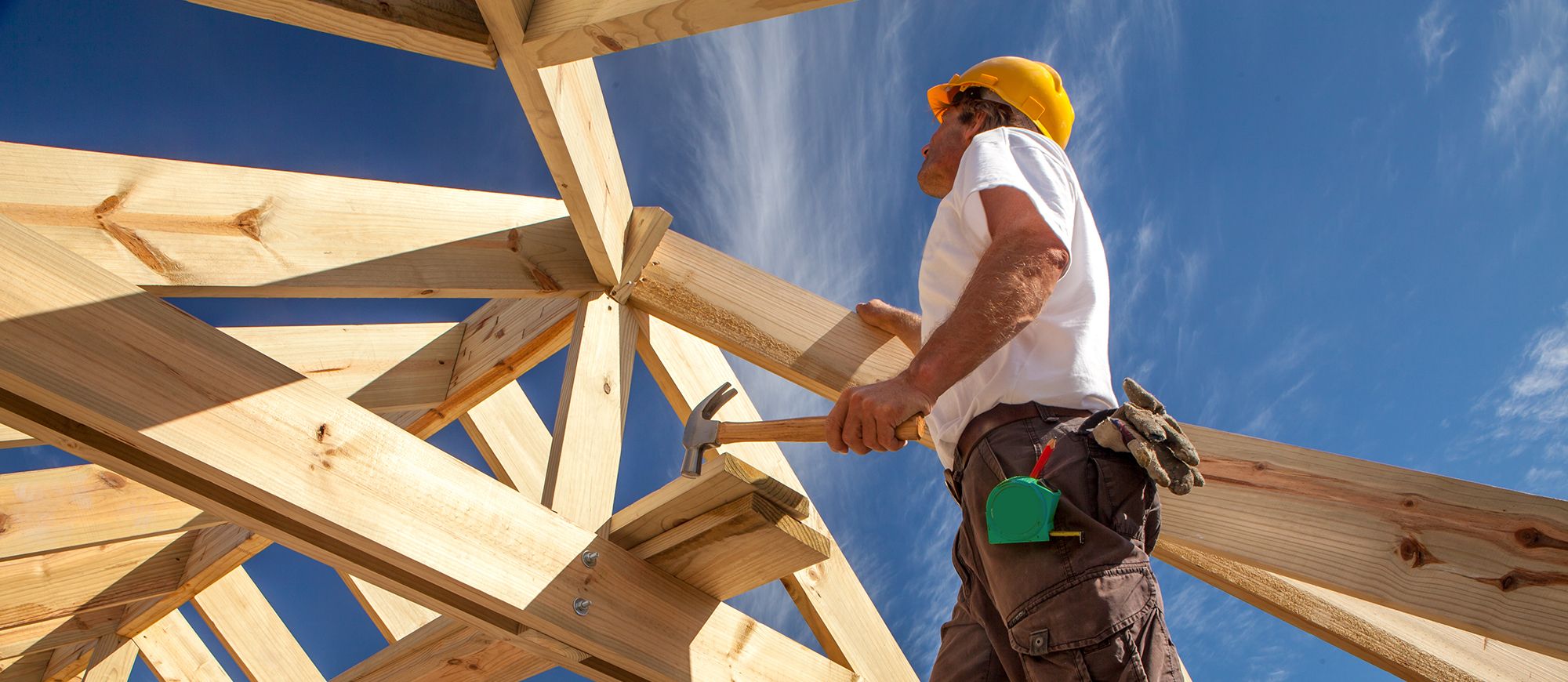 Ein Mann arbeitet an einem Holzdach und befestigt die Dachbalken sorgfältig